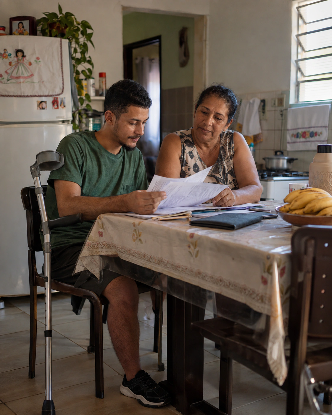 Homem conferindo documentos com a mãe, com uma muleta ao lado.